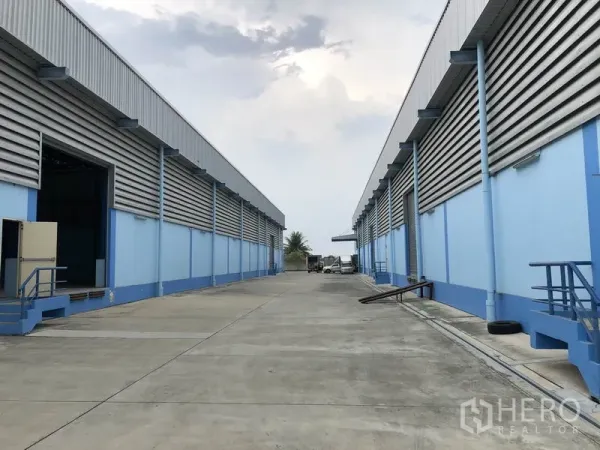 Warehouse for rent in Samut Prakan - Wide internal driveway between two blue warehouse blocks with a 12.5 m road in Bang Bo.