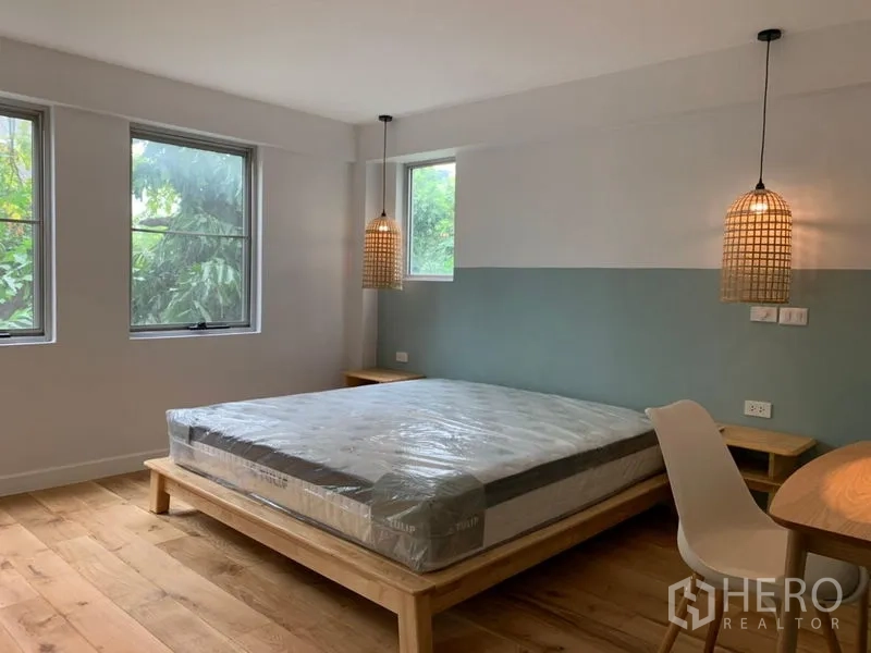 คอนโด ขายในWatthana, Bangkok - ห้องนอนหลักเตียงไม้ แขวนโคมหวาย และวิวสวน