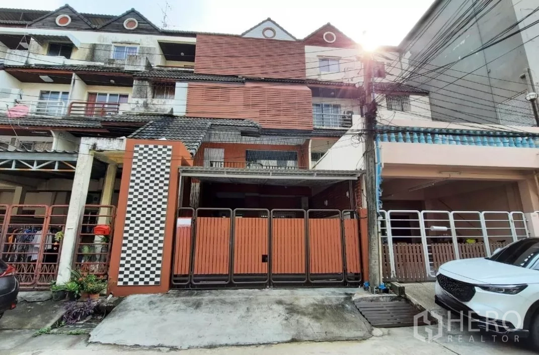 Townhouse for sale in Suan Luang, Bangkok - Front view of the townhouse with folding metal gate and driveway