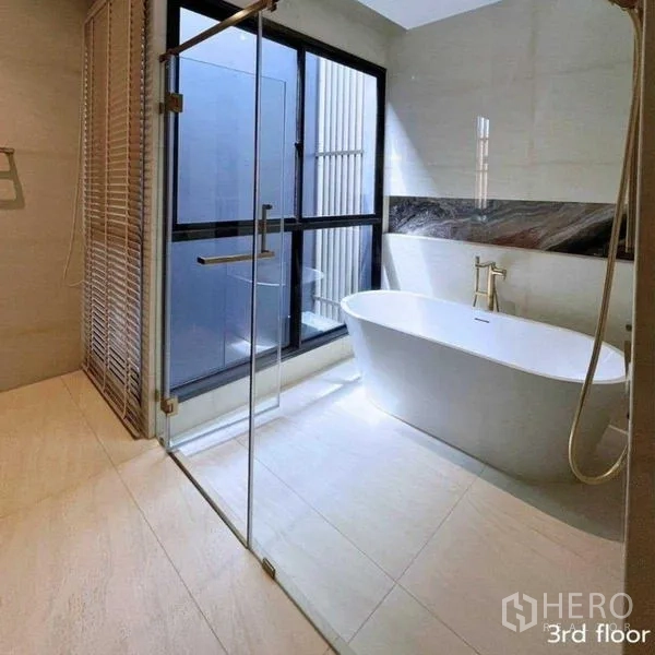 Detached House for rent in Bang Kapi, Bangkok - Bathroom with freestanding bathtub beside window and separate glass shower.
