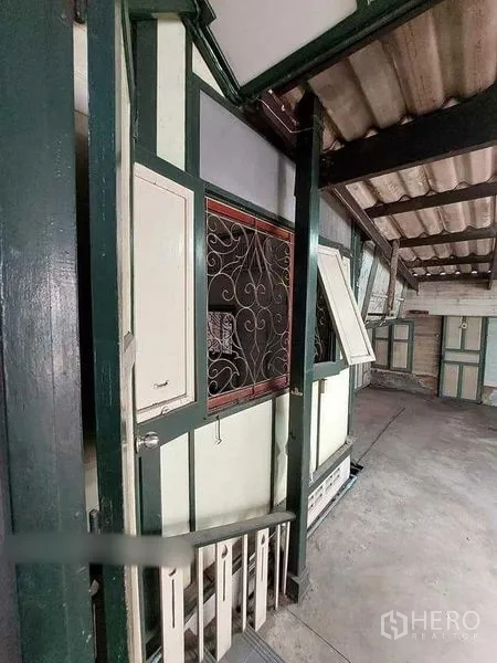 Detached House for rent in Bang Rak, Bangkok - Side exterior corridor with decorative metal grille window and corrugated roof.