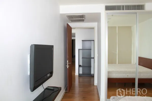 公寓 出租在Sathon, Bangkok - 走廊挂壁电视，通向带移门与置物架的明亮卧室。