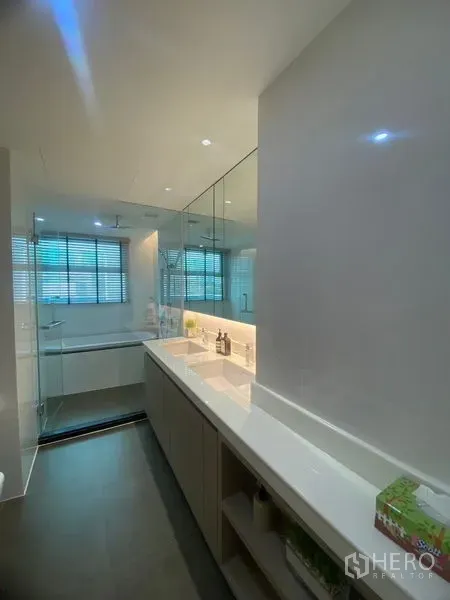 Condominium for rent in Watthana, Bangkok - Contemporary bathroom with a long vanity, illuminated mirror, and glass-enclosed shower beside a window.