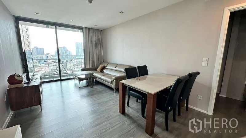 Condominium for rent - Spacious lounge with sofa, TV unit, and dining set facing a wide balcony and skyline view.