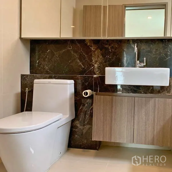 คอนโด ให้เช่า - ห้องน้ำสไตล์โมเดิร์น มีโถสุขภัณฑ์ อ่างล้างหน้า ตู้กระจก และผนังหินอ่อนสีเข้ม