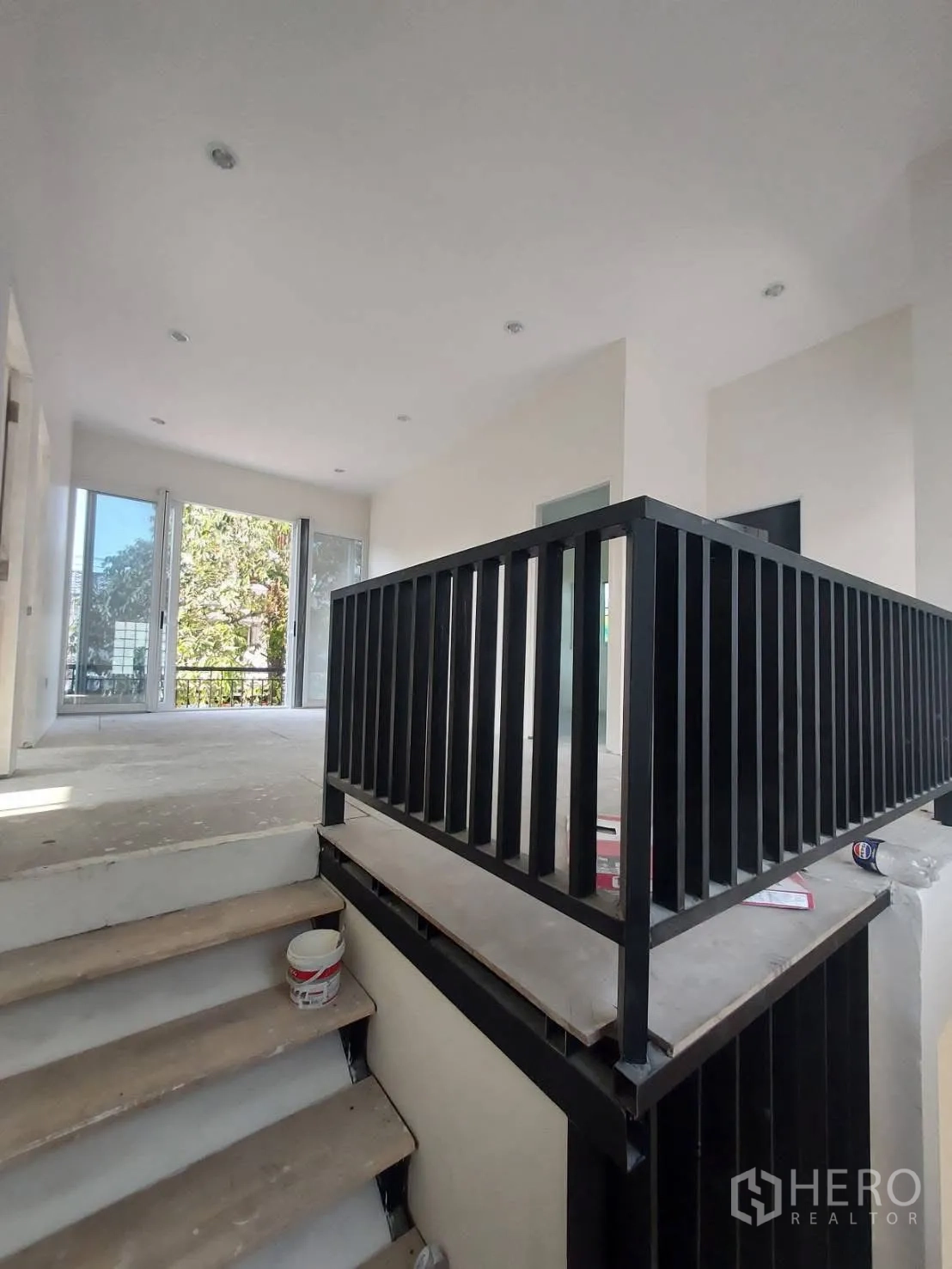 Detached House for rent in Watthana, Bangkok - Staircase with black metal railing leading to a sunny landing with large windows.