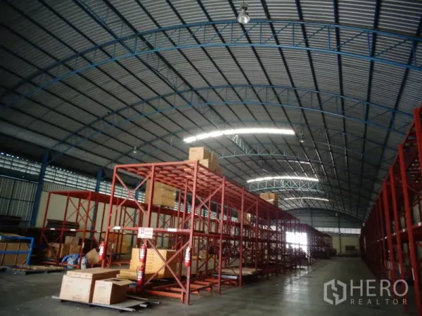Warehouse for rent or sale in Lat Lum Kaeo, Pathum Thani - Warehouse racks with stacked boxes and fire extinguishers along polished concrete floors.