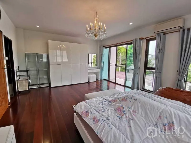 Detached House for rent in Prawet, Bangkok - Master bedroom opening to balcony via sliding glass doors, chandelier and white wardrobes.