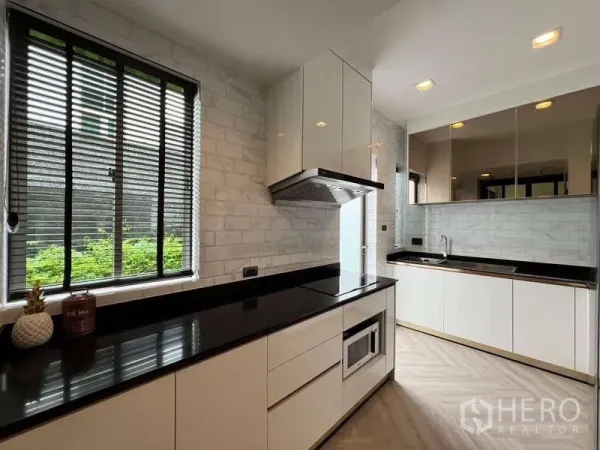 บ้าน ให้เช่าหรือขายในLat Krabang, Bangkok - ครัวสไตล์โมเดิร์น เคาน์เตอร์หินสีดำ ตู้สีขาว และหน้าต่างมู่ลี่