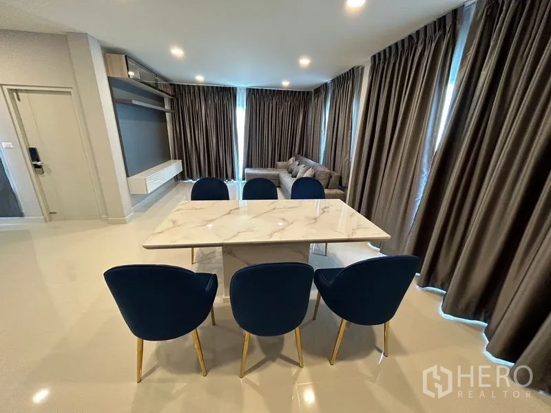 Detached House for rent in Bang Phli, Samut Prakan - Dining area with marble table and blue chairs next to living room.