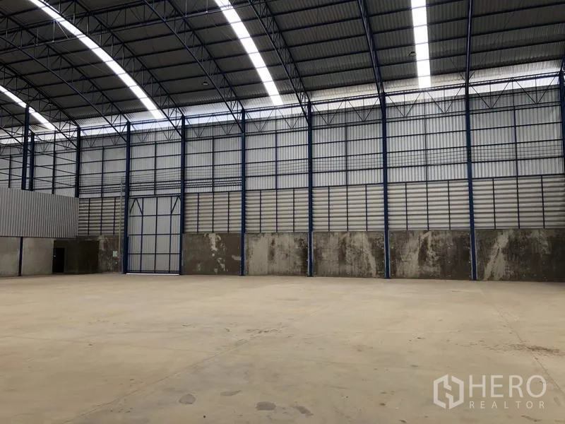 工厂 出租在Lat Lum Kaeo, Pathum Thani - 工厂内部空间宽敞，拱形钢屋顶与采光带，地面为混凝土。