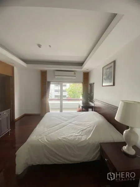 Condominium for rent - Master bedroom with wood flooring, bedside table and sliding balcony doors providing natural light.
