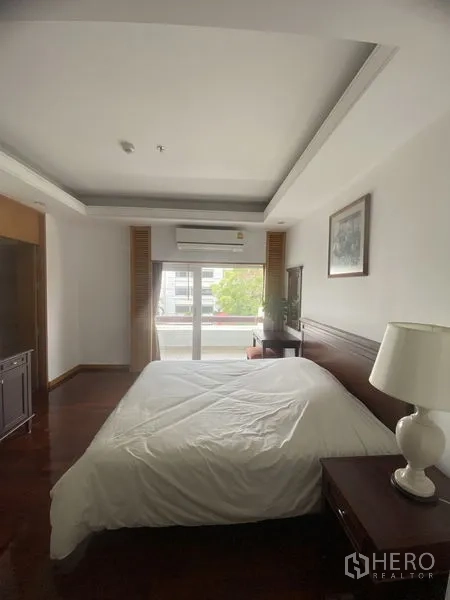 Condominium for rent - Master bedroom with wood flooring, bedside table and sliding balcony doors providing natural light.