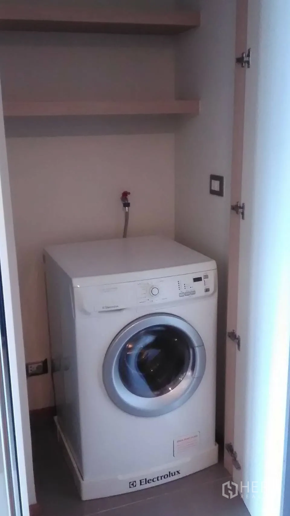 Condominium for rent or sale in Bang Rak, Bangkok - Laundry closet with a front-loading washing machine and shelves.