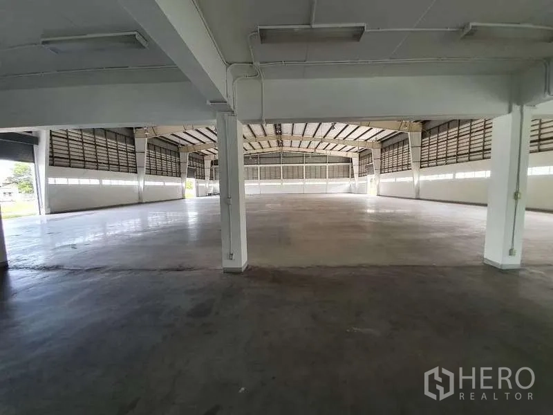 Factory for rent in Mueang Samut Prakan, Samut Prakan - Spacious factory interior with high clear-span ceiling, white columns and polished concrete floor with natural side lighting.