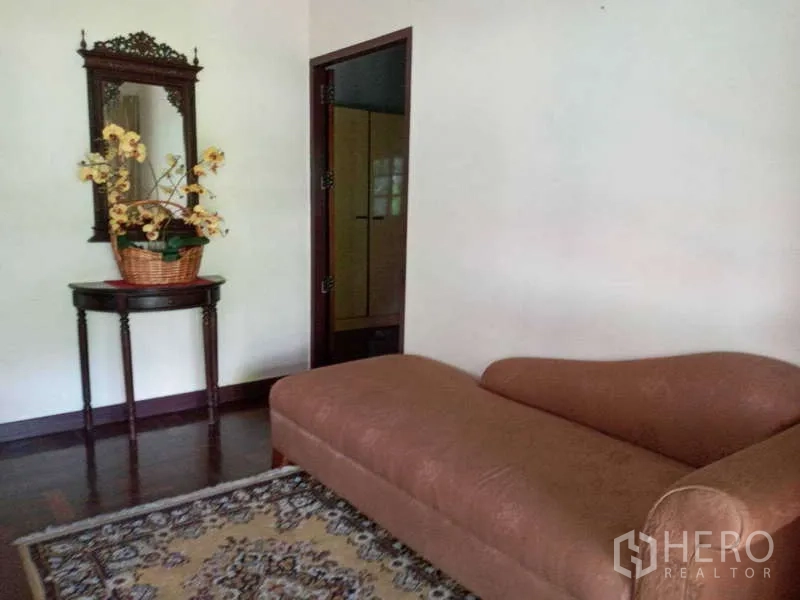 Detached House for rent in Khlong Toei, Bangkok - Cozy sitting room with chaise lounge, mirror and area rug.