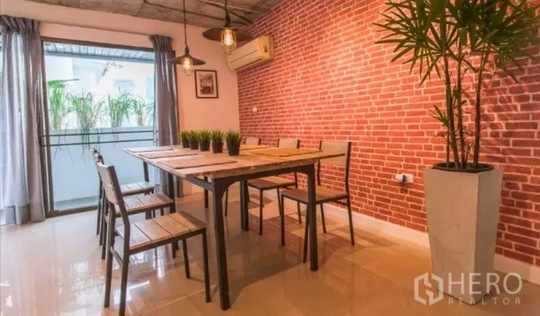 Condominium for rent in Watthana, Bangkok - Dining zone facing the balcony with floor-to-ceiling curtains and potted plant.