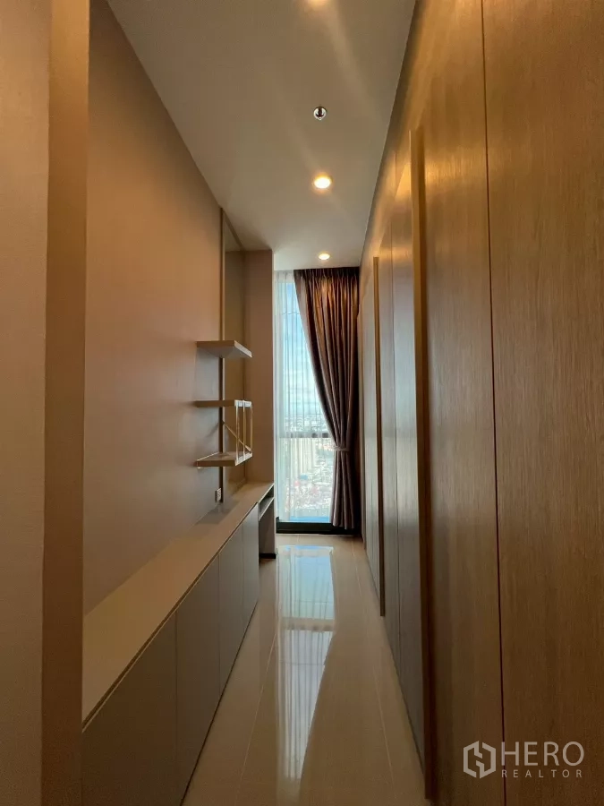 Condominium for rent in Phra Khanong, Bangkok - Built-in corridor with cabinets and shelving leading to window and city view.
