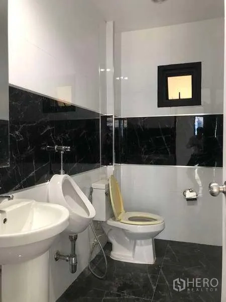 Factory for rent or sale in Bang Phli, Samut Prakan - Clean tiled bathroom with toilet, urinal, sink and small ventilation window.