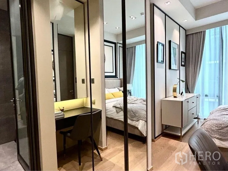Condominium for rent in Pathum Wan, Bangkok - Walk-through dressing area with mirrored wardrobes and a compact work desk.