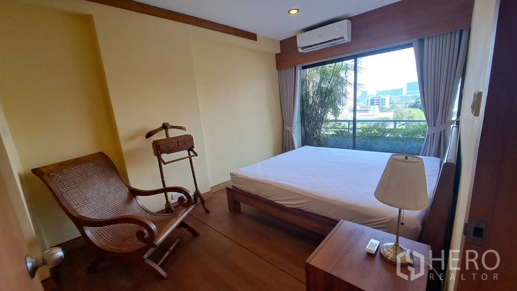 Condominium for rent in Khlong Toei, Bangkok - Bedroom with large window, balcony greenery, and city outlook.