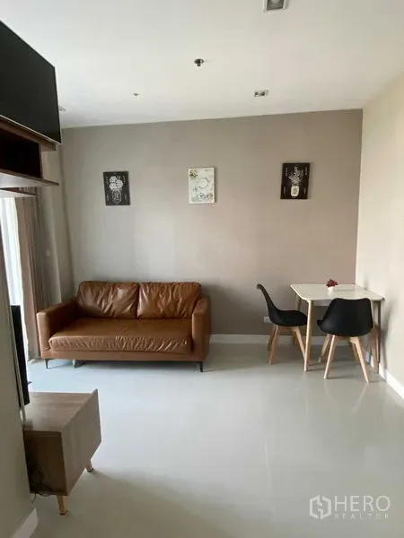 Condominium for rent in Phra Khanong, Bangkok - Open-plan living area with leather sofa and two-seat dining nook.