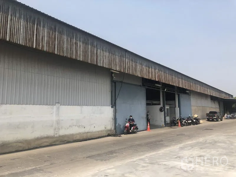 Warehouse for rent in Nonthaburi - Side view of the warehouse facade with multiple loading entrances and driveway access.