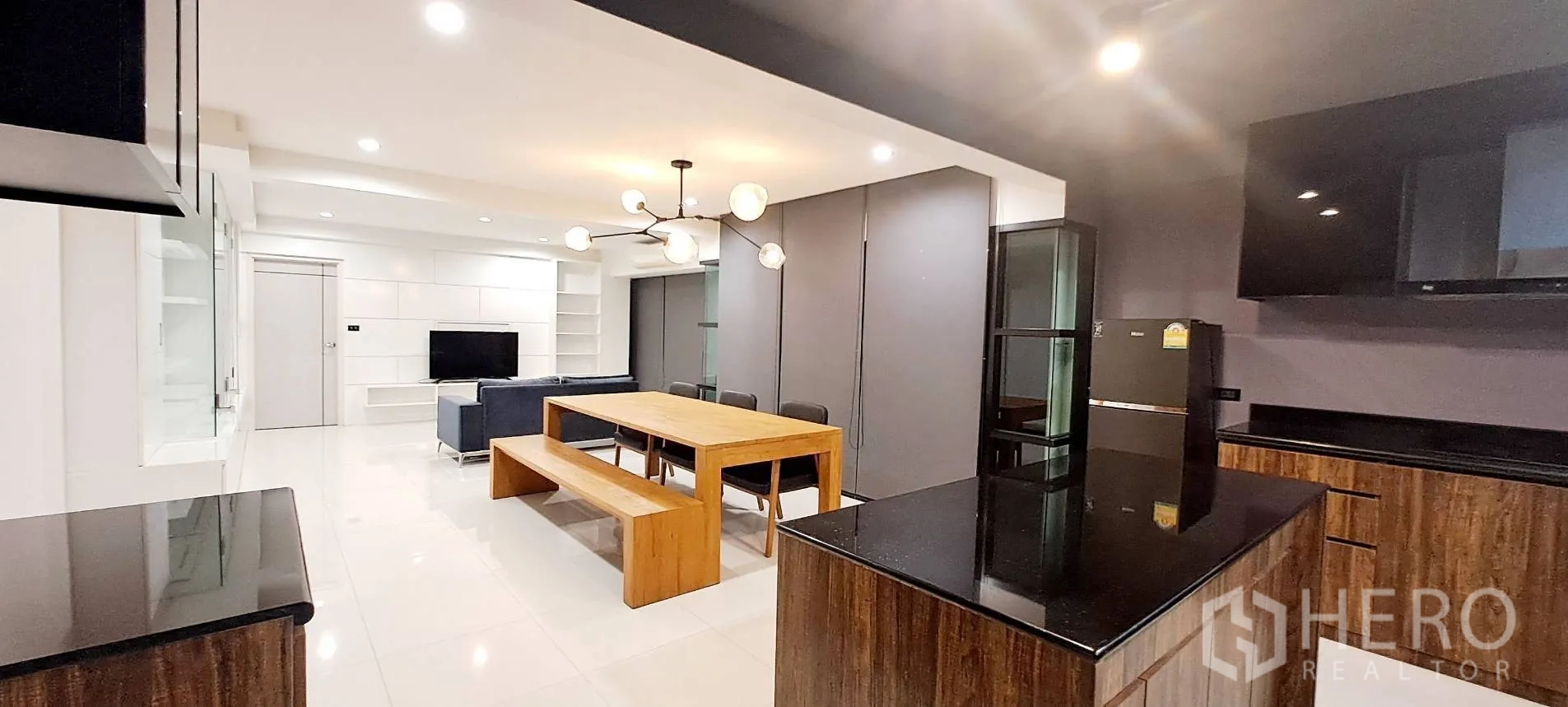 Apartment for rent in Phra Khanong, Bangkok - View from kitchen toward sofa and dining in an open-plan layout.