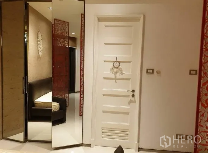 Condominium for sale in Khlong Toei, Bangkok - Entry hallway with a white panel door, mirrored wardrobe panels, and a sofa nook.