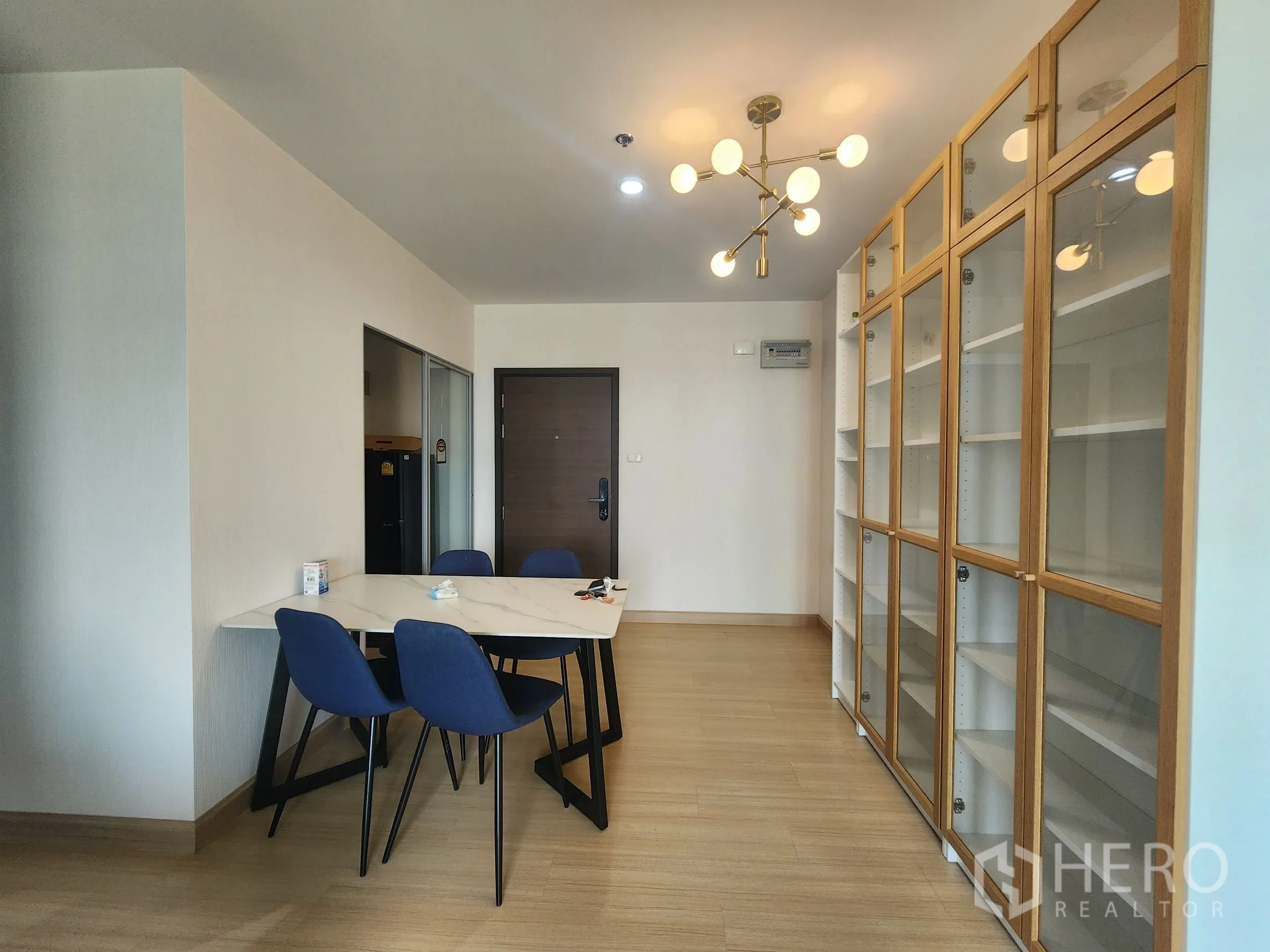 คอนโด for rent in Huai Khwang, Bangkok - โซนทานอาหาร โต๊ะท็อปหินอ่อน เก้าอี้สีน้ำเงิน ตู้บานกระจก และโคมไฟดีไซน์โมเดิร์น