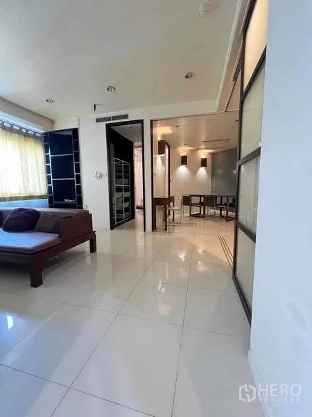 Condominium for rent in Ratchathewi, Bangkok - Open‑plan lounge and dining area with sliding glass partitions and recessed lighting.