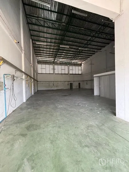 Warehouse for rent in Phra Samut Chedi, Samut Prakan - Warehouse interior from the opposite end showing ventilation windows and service piping.