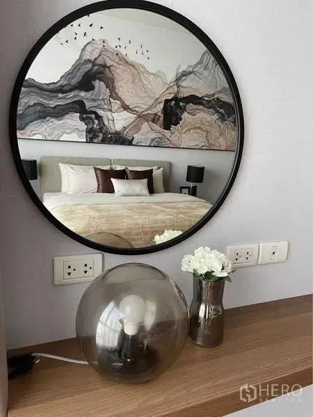 คอนโด ให้เช่าในPathum Wan, Bangkok - กระจกเงากรอบกลมเหนือคอนโซล สะท้อนภาพห้องนอนและหัวเตียงลายศิลป์