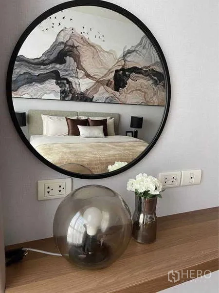 คอนโด ให้เช่าในPathum Wan, Bangkok - กระจกเงากรอบกลมเหนือคอนโซล สะท้อนภาพห้องนอนและหัวเตียงลายศิลป์