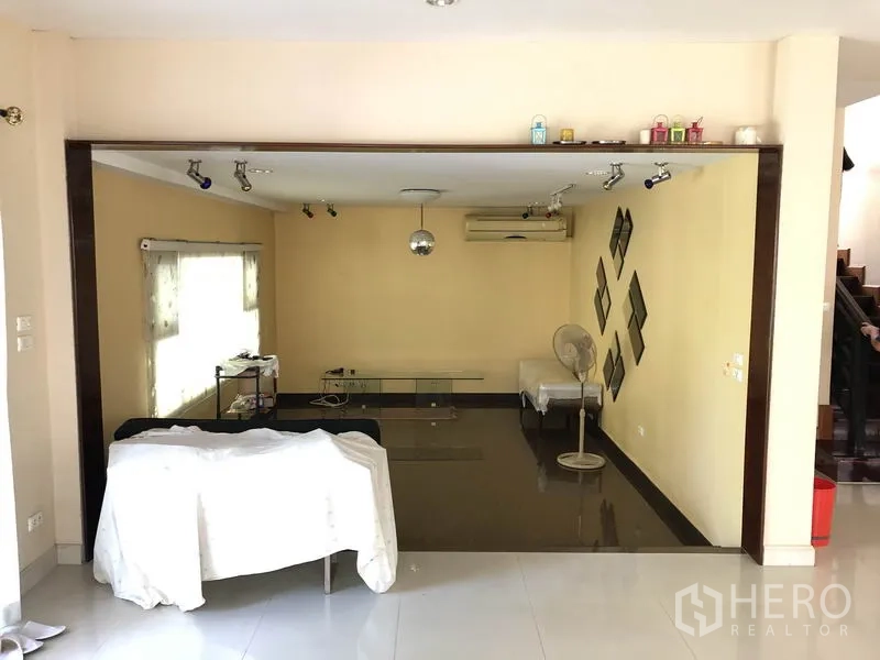 独立式住宅 出租或出售在Bang Kapi, Bangkok - 下沉式客厅，轨道射灯与米色背景墙，配百叶窗。