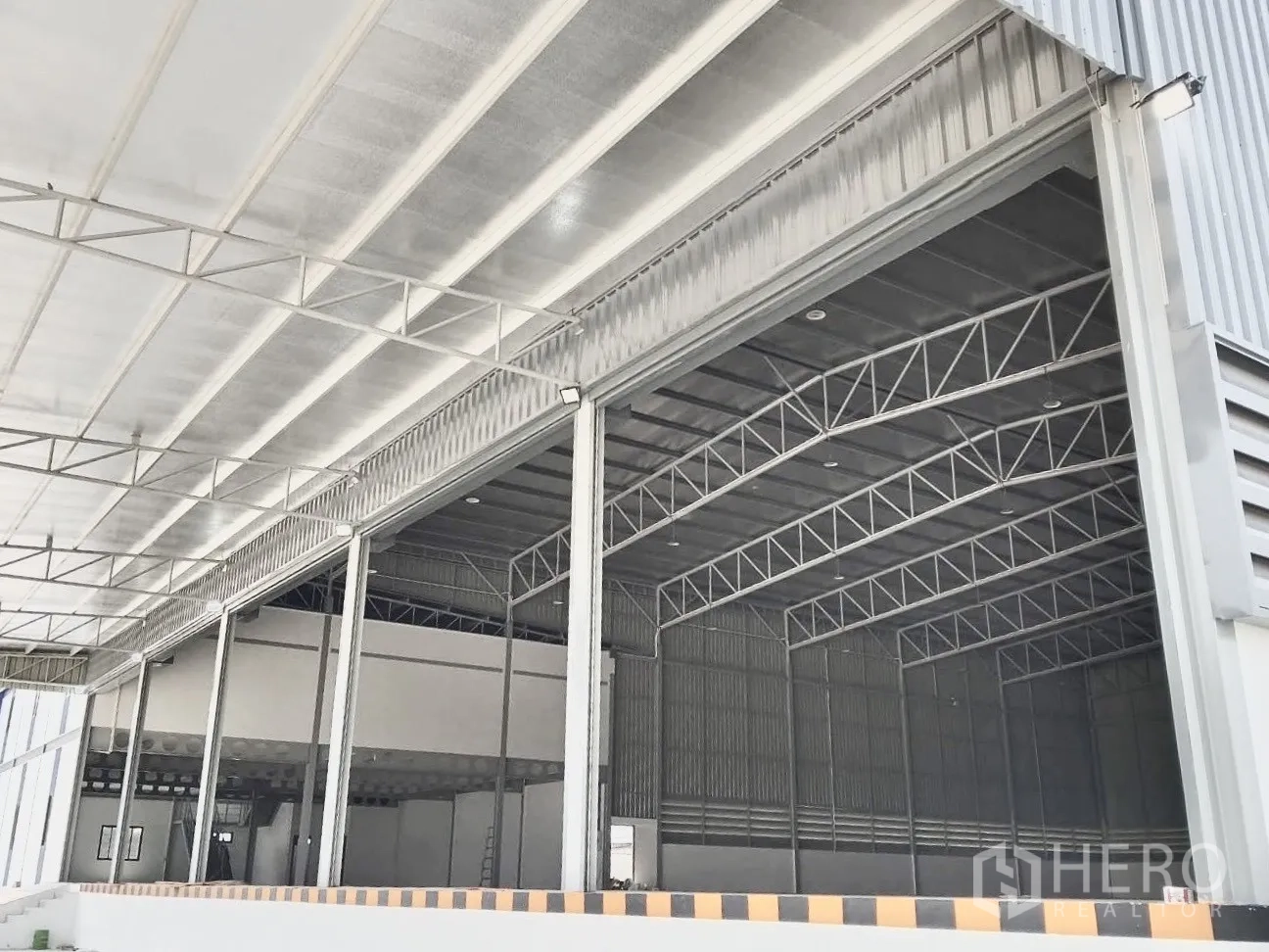 Warehouse for rent in Bang Bo, Samut Prakan - Covered loading area with roller shutters and a raised dock for trucks.