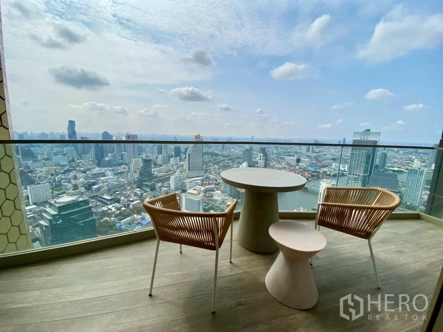คอนโด ให้เช่าในKhlong San, Bangkok - ชุดโต๊ะเก้าอี้ที่ระเบียง มองเห็นแม่น้ำและสกายไลน์ผ่านราวกระจก