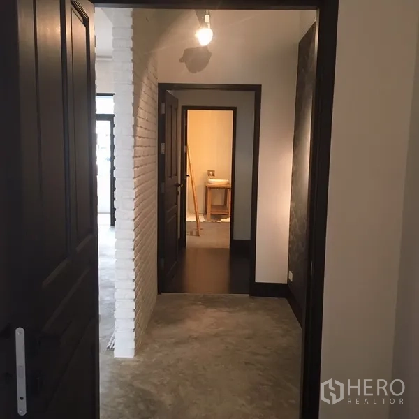 คอนโด ให้เช่าในWatthana, Bangkok - โถงภายใน เสาอิฐทาสีขาว ประตูหลายบาน และหลอดไฟเปลือยบนเพดาน.