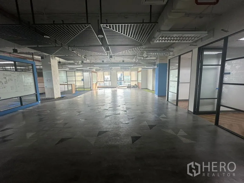 Office Space for rent in Bang Rak, Bangkok - Open office area with ceiling baffles, glass rooms on the right, and polished floor.