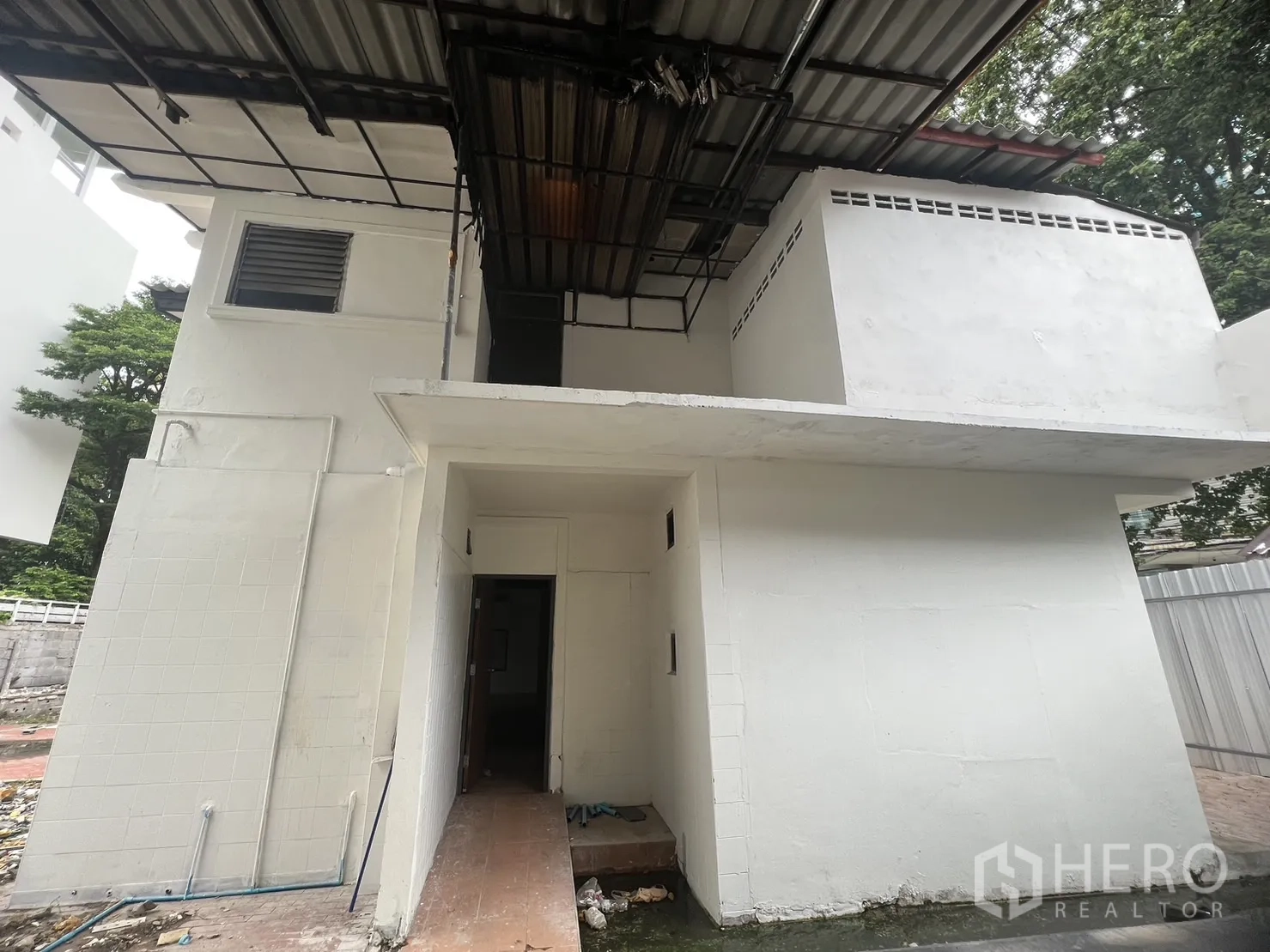 零售空间 出租在Watthana, Bangkok - 两层白色建筑外立面，金属屋顶与遮雨棚入口，适合做商铺。