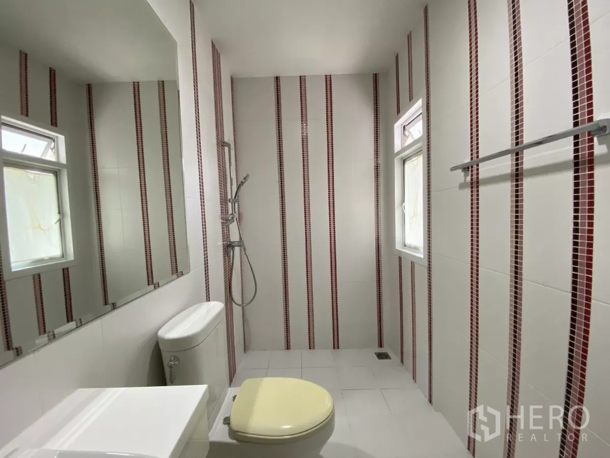 บ้าน ให้เช่าหรือขายในLak Si, Bangkok - ห้องน้ำลวดลายโมเสกเส้นตั้งสีแดง มีฝักบัวและช่องหน้าต่างระบายอากาศ.