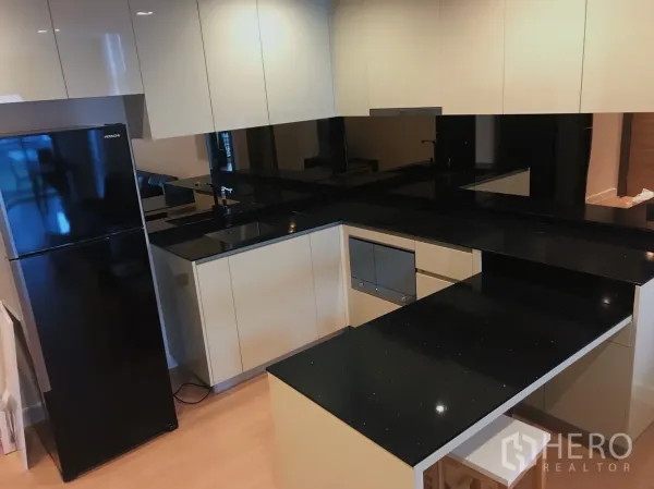 公寓 出租或出售在Bang Rak, Bangkok - 现代U型厨房，亮面橱柜与黑色石材台面