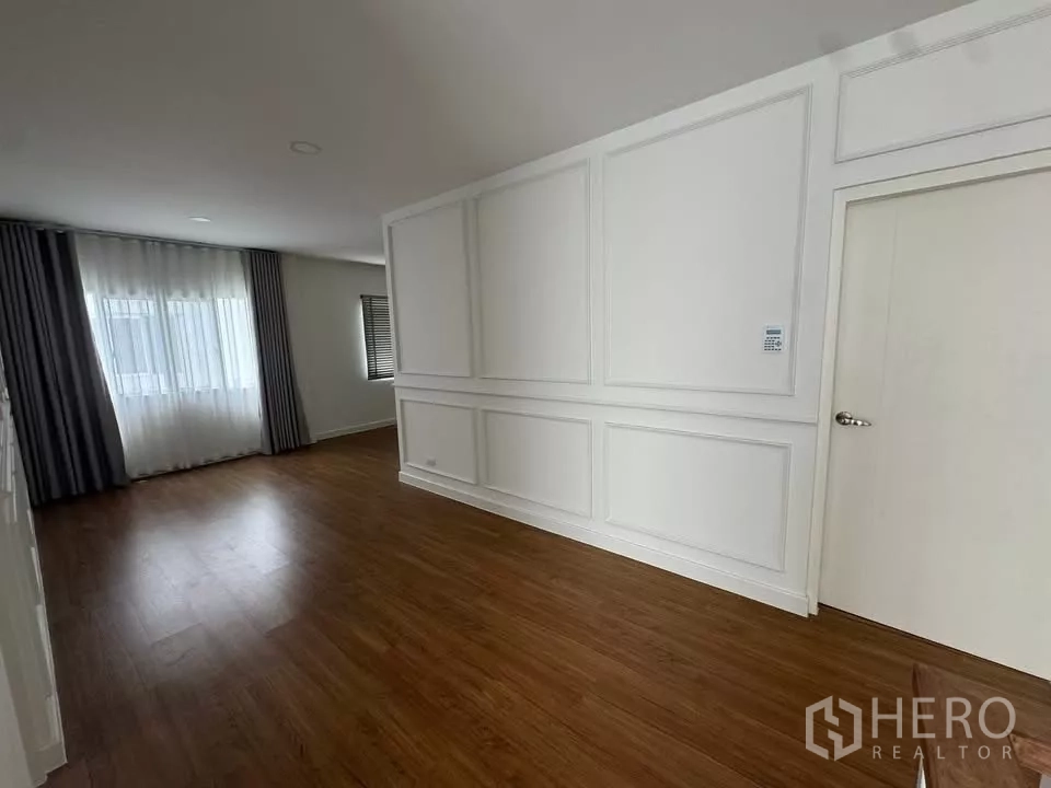 Detached House for rent or sale in Bang Bo, Samut Prakan - Large bedroom with wide windows, curtains, and warm wood flooring.