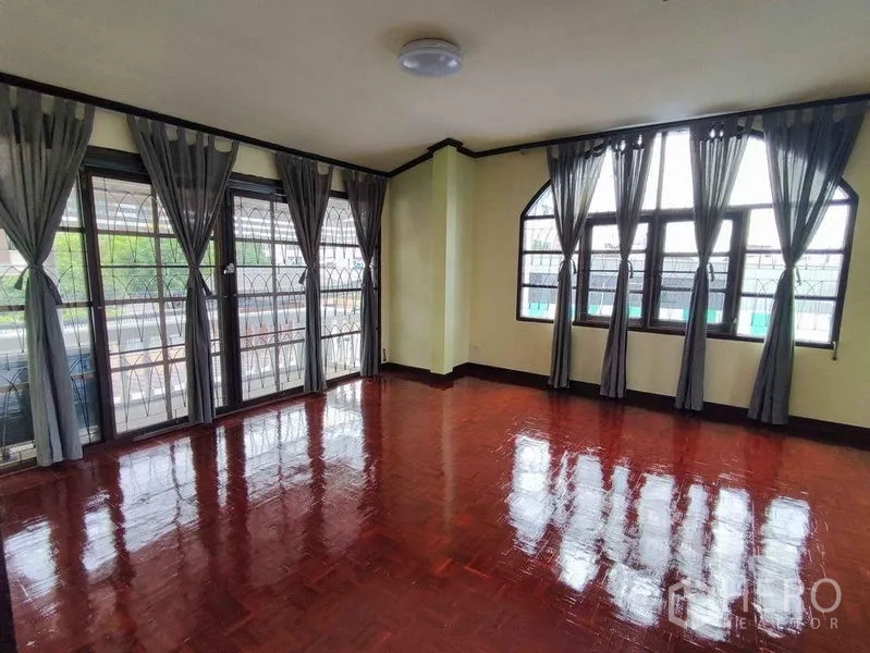 Detached House for rent in Khlong Toei, Bangkok - Bright upper room with curtains, many windows and balcony access over polished hardwood floors.
