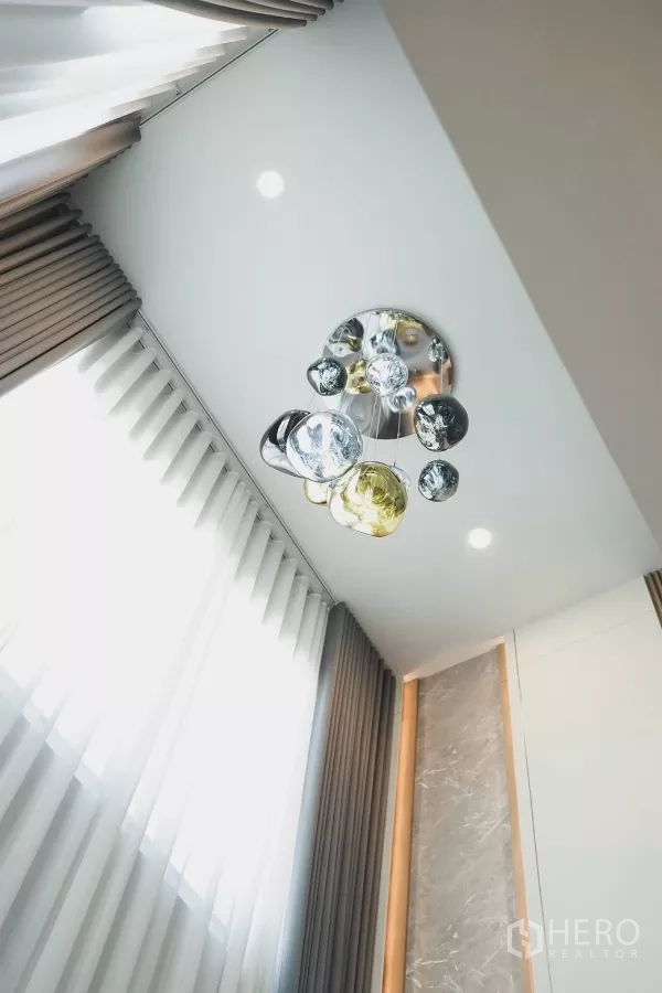 独立式住宅 出租在Bang Phli, Samut Prakan - 高挑天花上的设计感吊灯与整面窗帘。