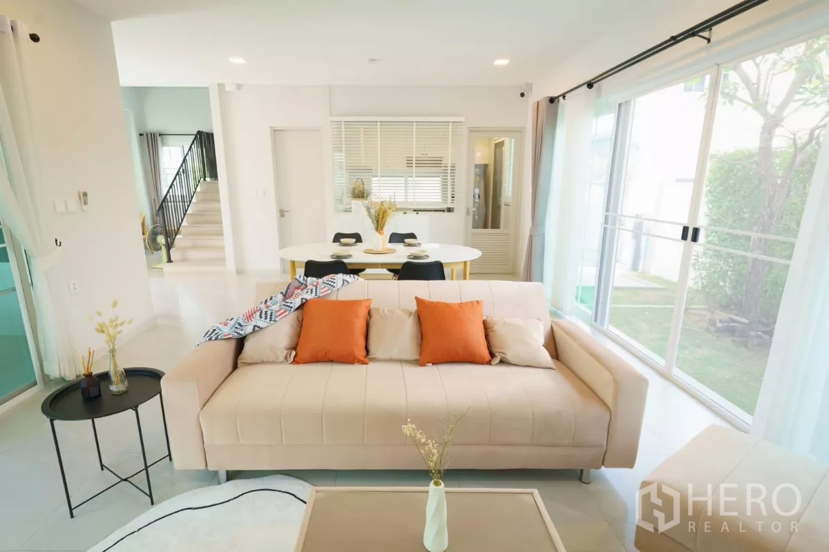 Detached House for rent in Bang Phli, Samut Prakan - Living room view toward dining and kitchen with garden seen through windows.
