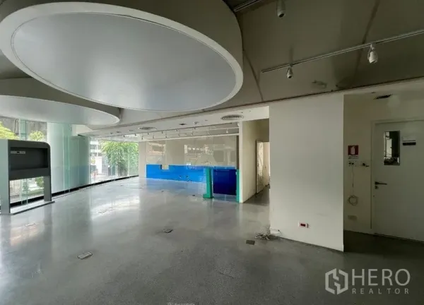 พื้นที่ขายปลีก ให้เช่า - ภายในพื้นที่ค้าปลีกแบบโอเพ่นแพลน กระจกเต็มบาน ไฟราง และพื้นคอนกรีตขัดมัน