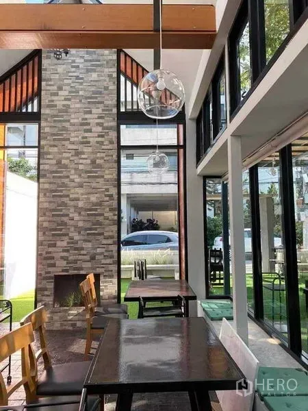 Retail Space for rent in Suan Luang, Bangkok - Glass-walled retail area with pendant lighting and a tall brick feature column overlooking a landscaped garden.