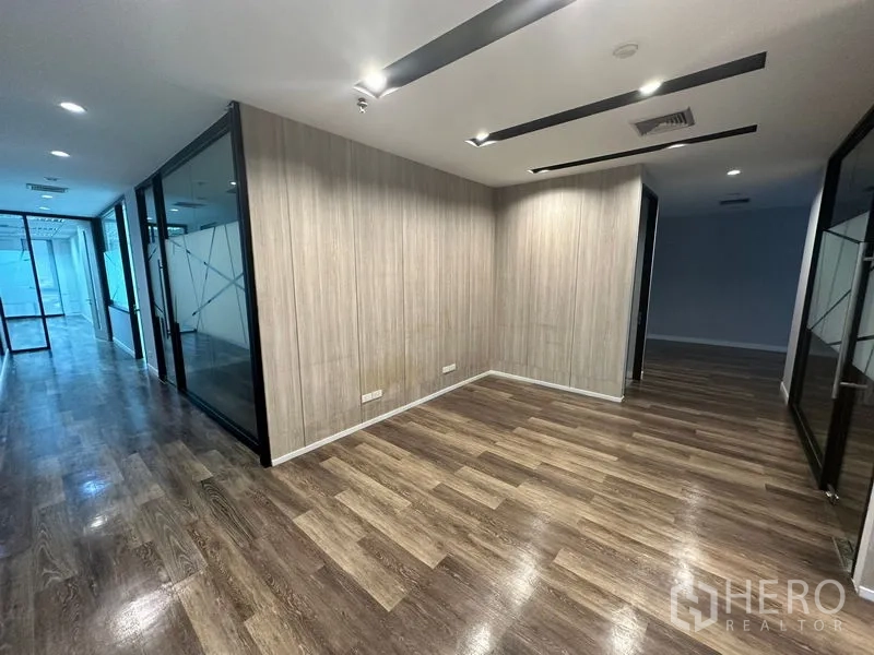 Office Space for rent - Hallway with recessed lighting, wood panel walls and glass-partitioned offices along a polished wood floor.