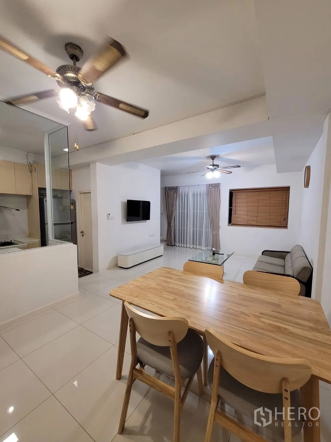 联排别墅 出租在Prawet, Bangkok - 餐区邻接客厅，吊扇与木质餐桌椅。